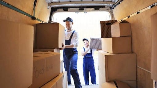 Two removal men load a van with boxes